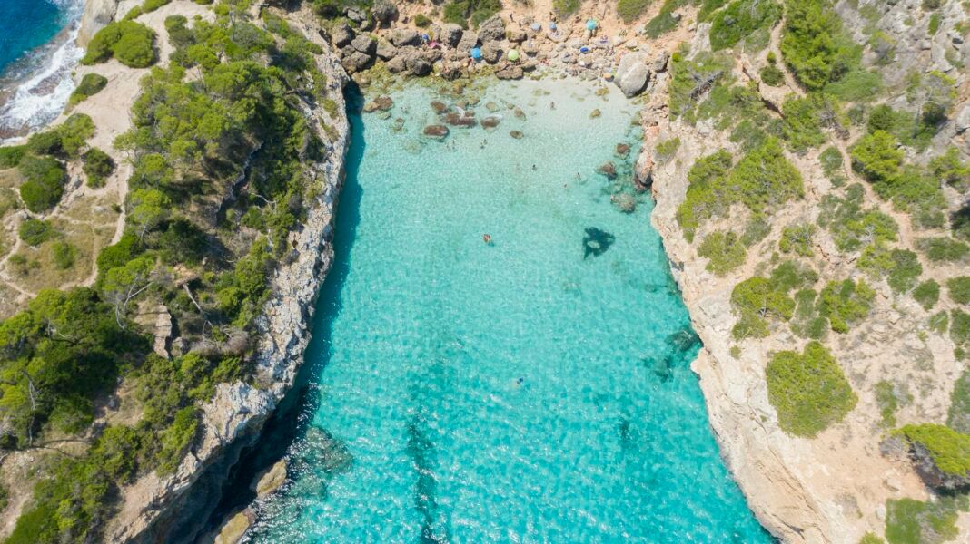 Breathtaking aerial view of Caló des Moro's turquoise waters and rocky shores in Mallorca, Spain.