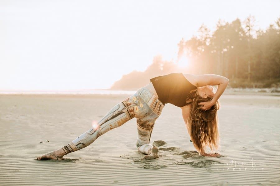 woman doing yoga poses at sunset on sandy beach