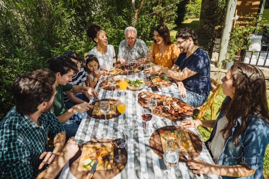Multi-generation family is sitting in the yard at dining table