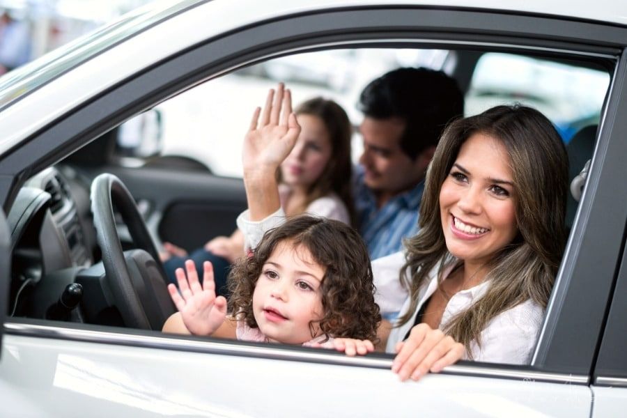 family sitting in new car and waving