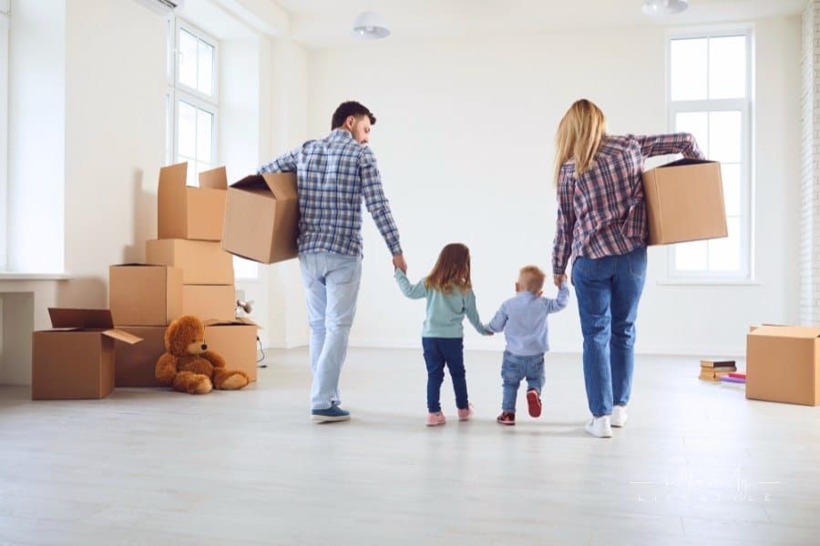 Happy Family with Children Moving with Boxes into a New House.