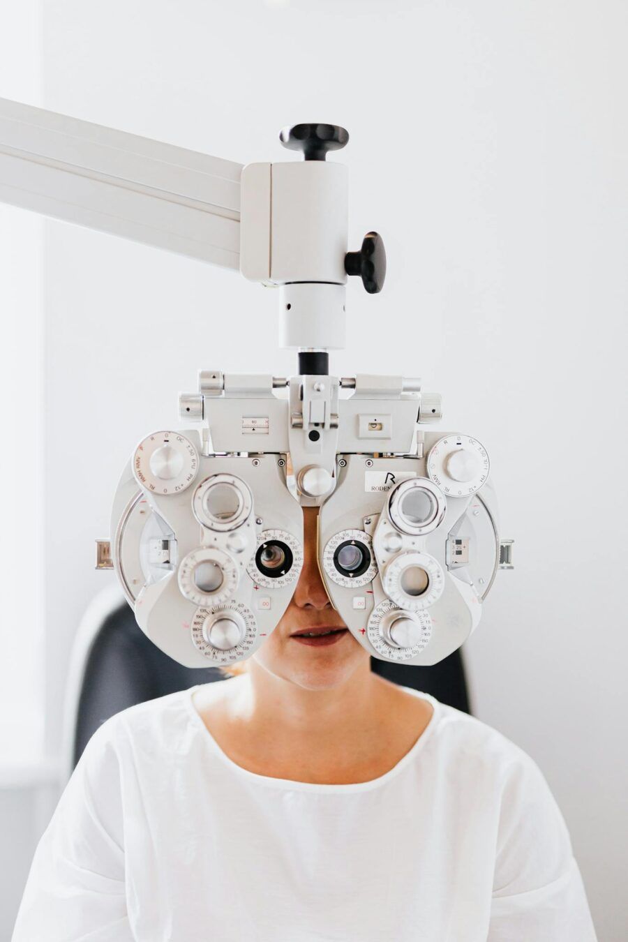 Close-up of a woman undergoing an eye examination using a phoropter in a clinic.