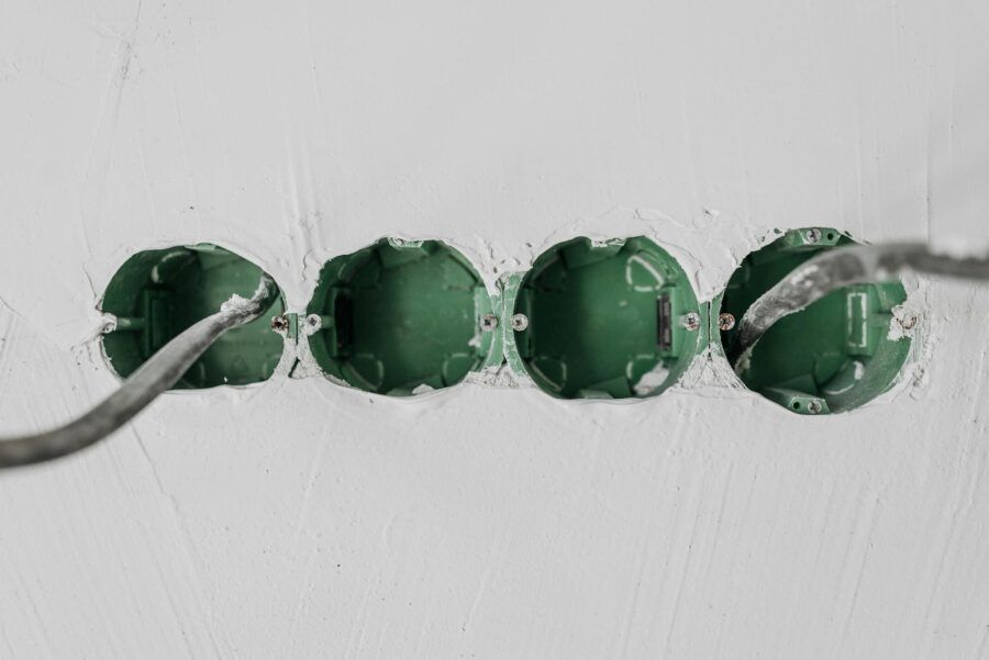 Close-up of green electrical boxes and wiring in a wall setup.