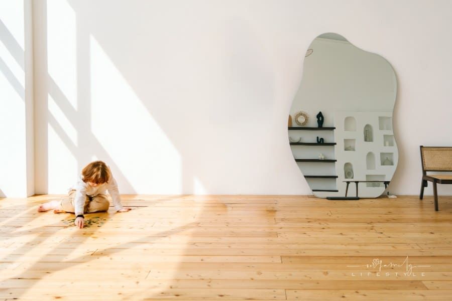 red-haired child putting a puzzle together on floor in shadow of large window