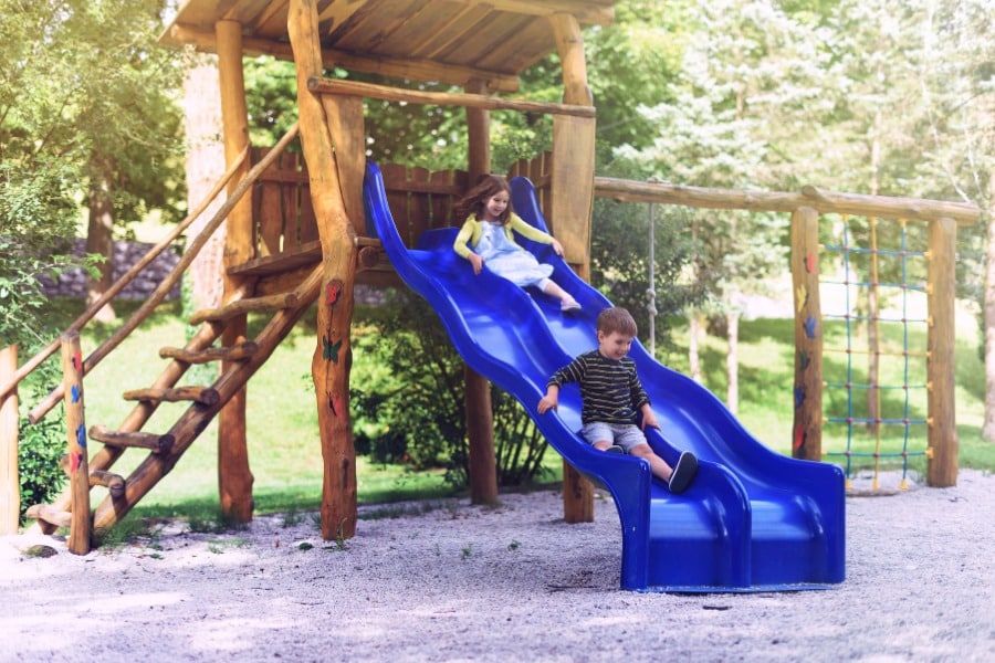 two kids sliding down backyard slides