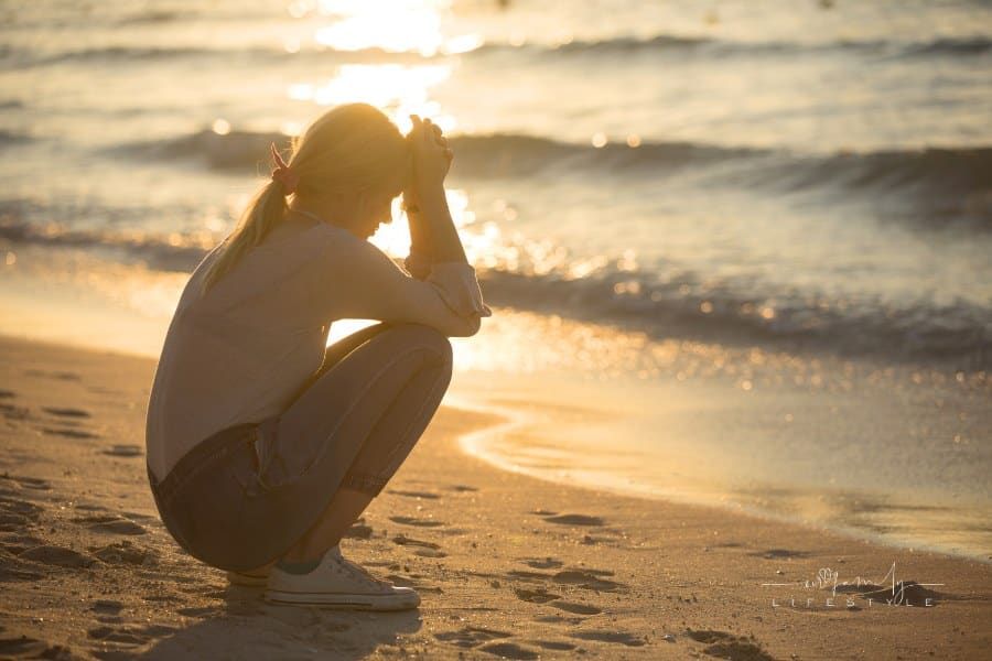 Sad woman alone at the beach during sunset. Love, loneliness and heartbreak.