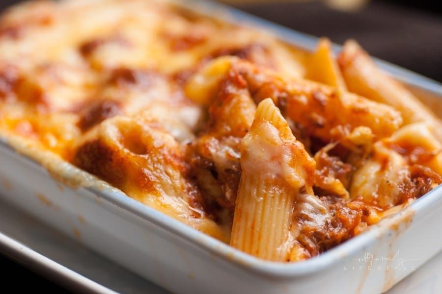 Baked penne pasta with tomato sauce and cheese in white bowl