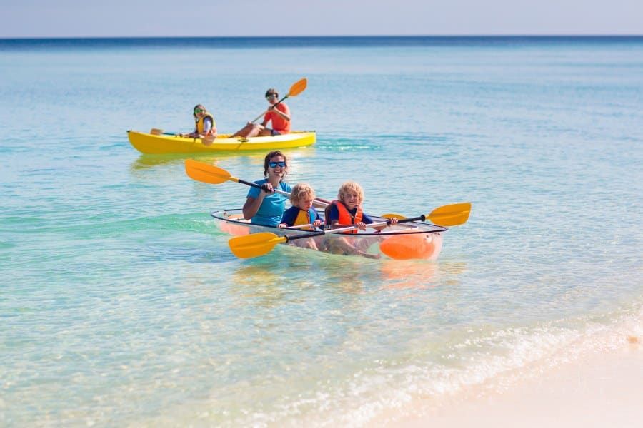 Kids kayaking with mom in ocean. Family in kayak in tropical sea