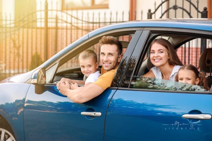 happy family of four looking out car windows