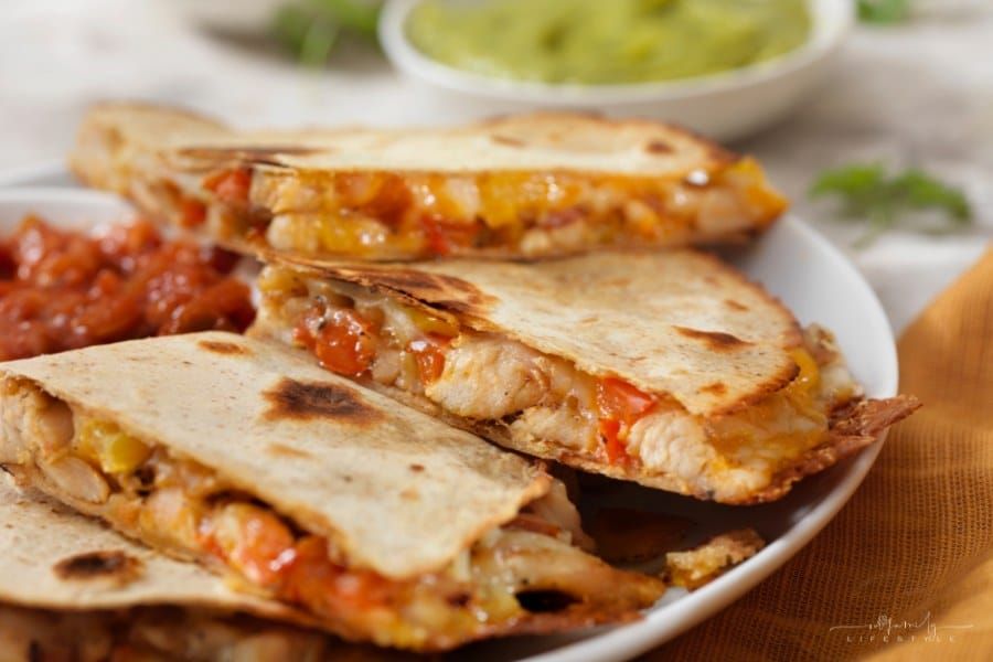 Cheesy Chicken Quesadillas on plate with bowl of guacamole in background