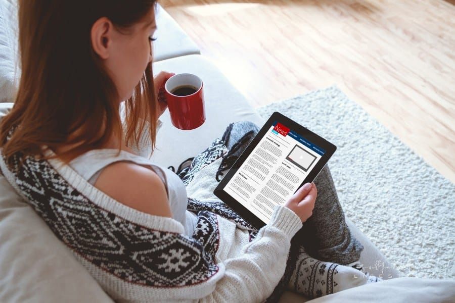 Woman reading news on tablet while drinking a cup of coffee
