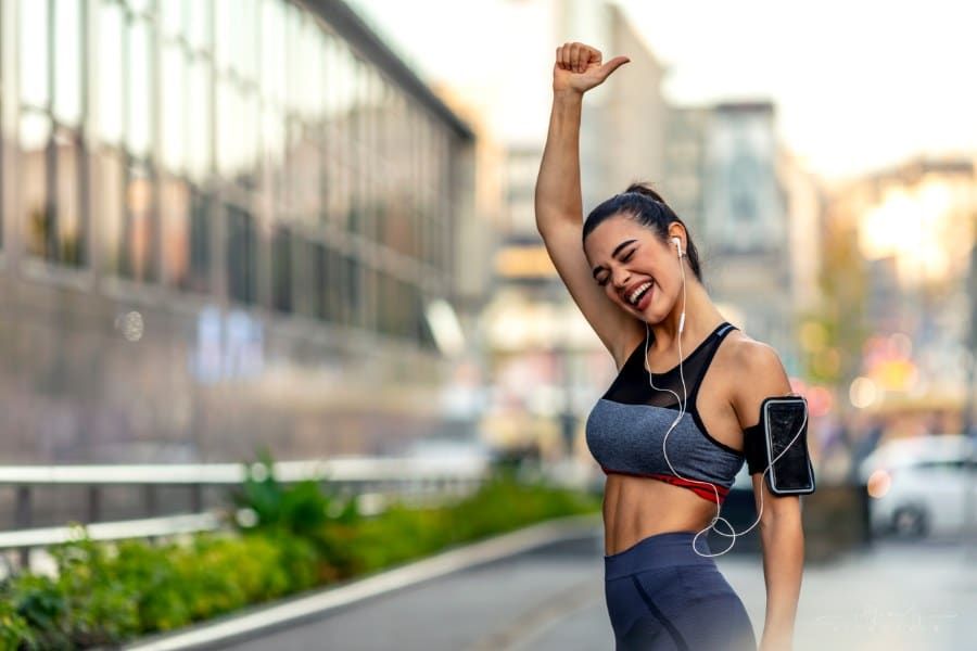 woman with one arm raised while listening to music after a run