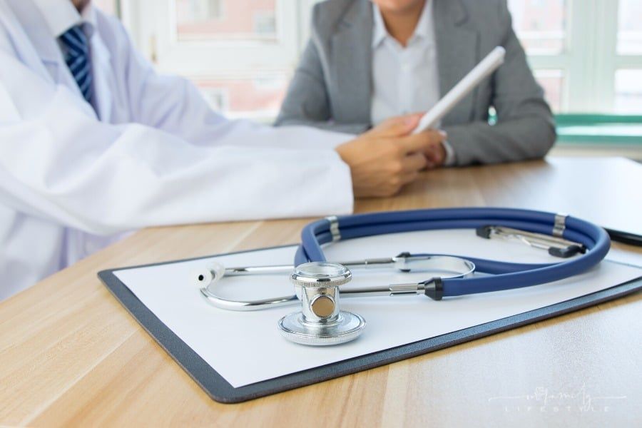 doctor looking at tablet while talking to patient