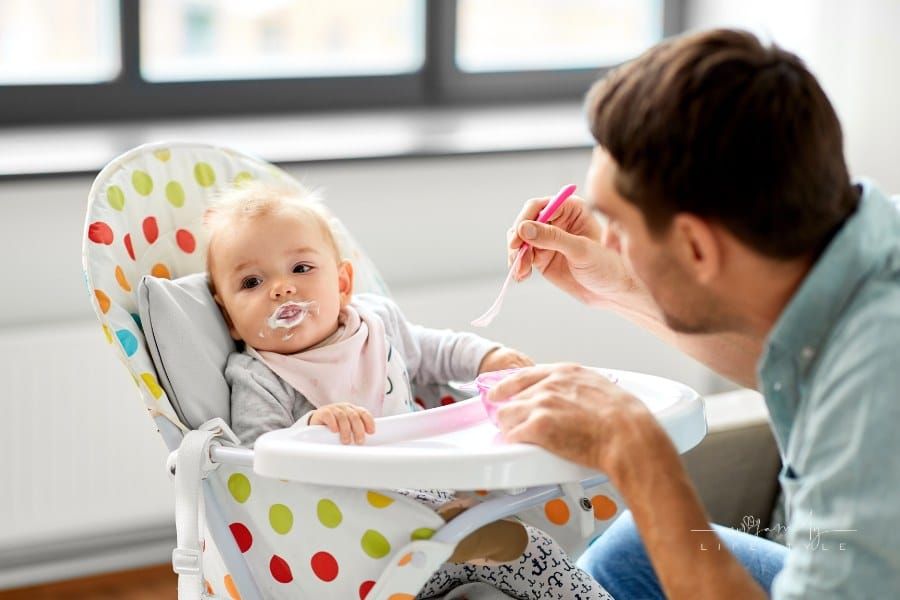 Father Feeding Baby in Highchair at Home