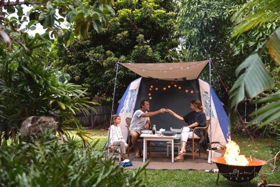 mom, dad and daughter backyard camping in a tent