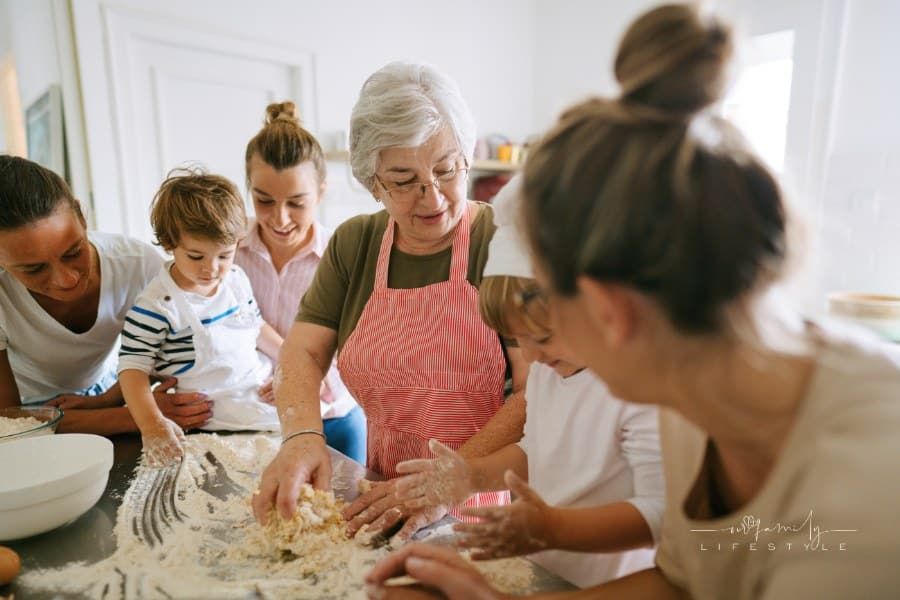 Photo of a happy multigenerational family preparing food in the kitchen; having a great time while kneading and enjoying each