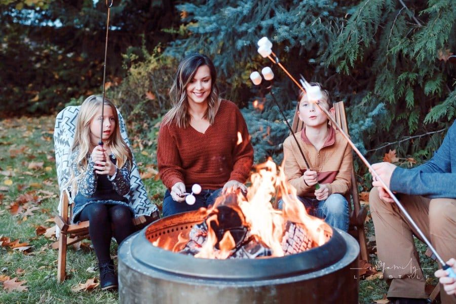 Family roasting marshmallows for smores around fire