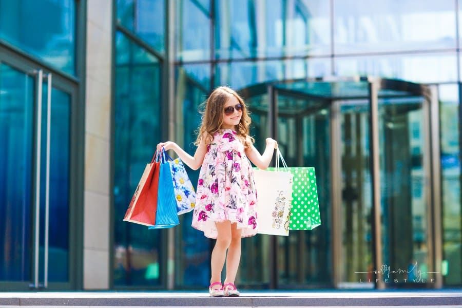 Cute little girl on shopping. Portrait of a kid with shopping bags.