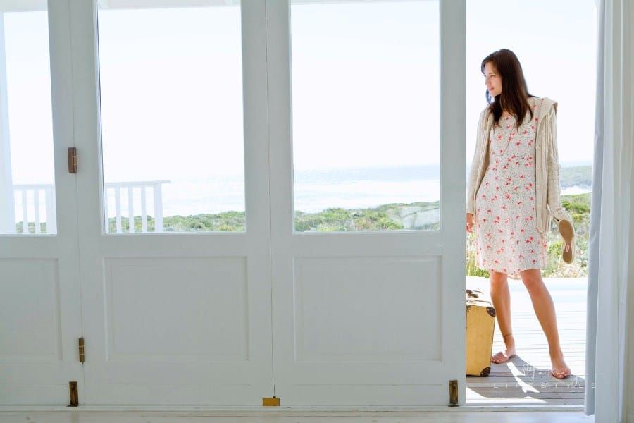 Woman arriving at beach house with suitcase