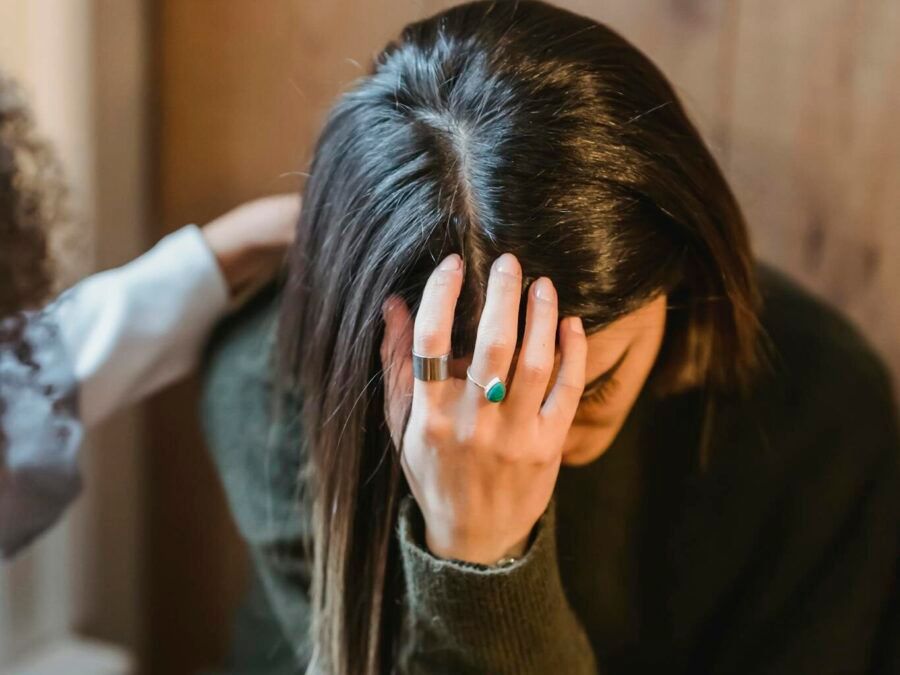 From above of young exhausted sad female in sorrow with supporting crop anonymous friend