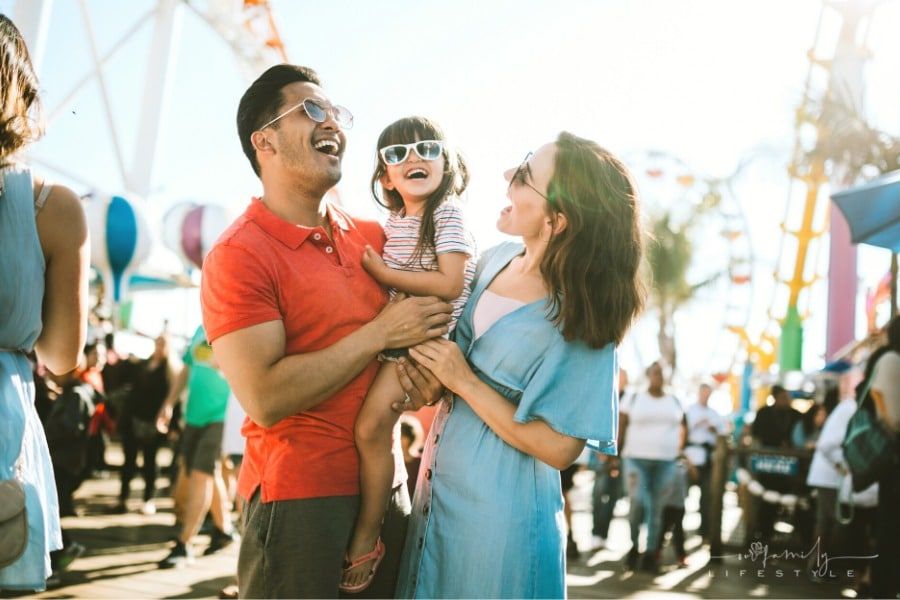 mom and dad with daughter laughing at street fair