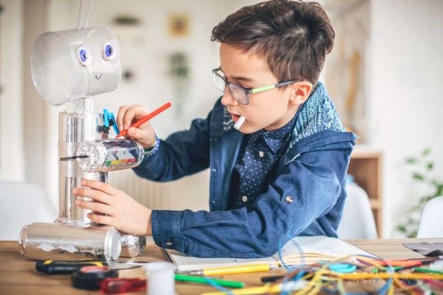 young boy making robot toy from recycled material