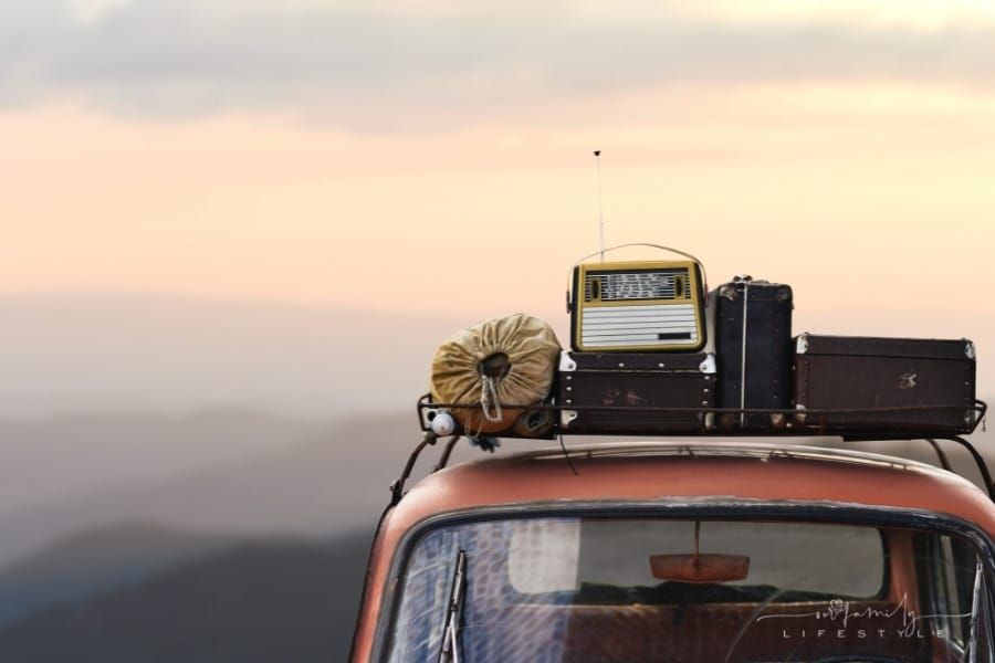 vintage car with roof rack and mountains in background
