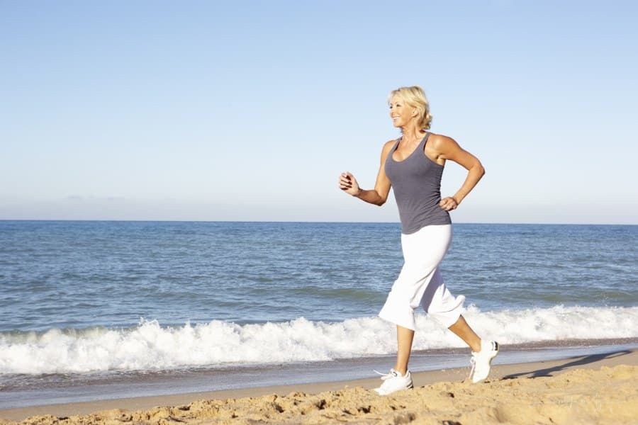 senior woman running on beach