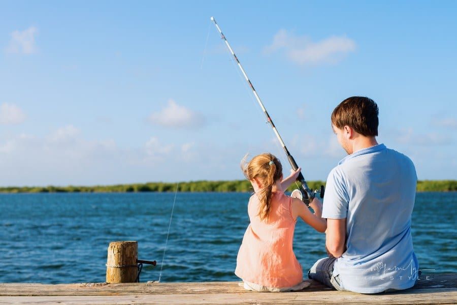 Family father and daughter fishing together from wooden dock