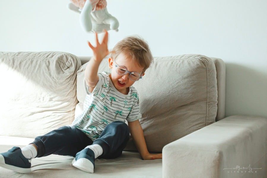 child with autism sitting on couch, sad and angry, throwing a stuffed animal