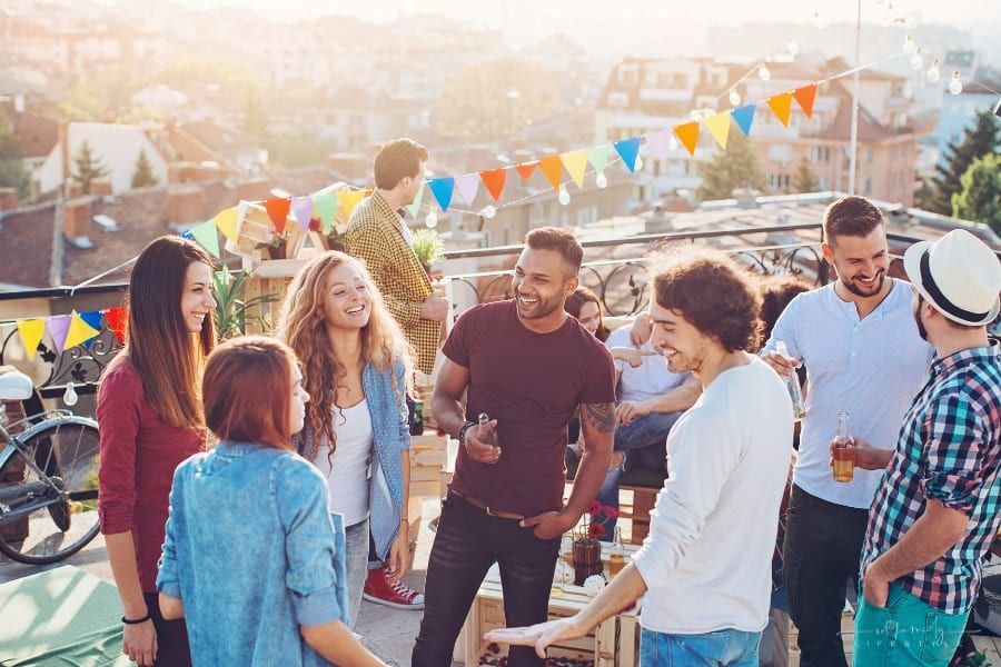 large social gathering with young people and drinks on the rooftop with decorations and food