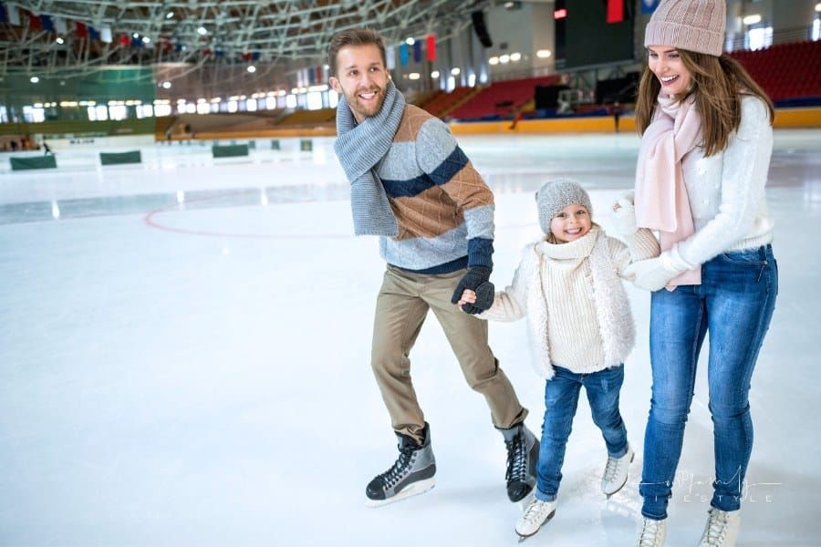 family ice skating happily together at an indoor rink