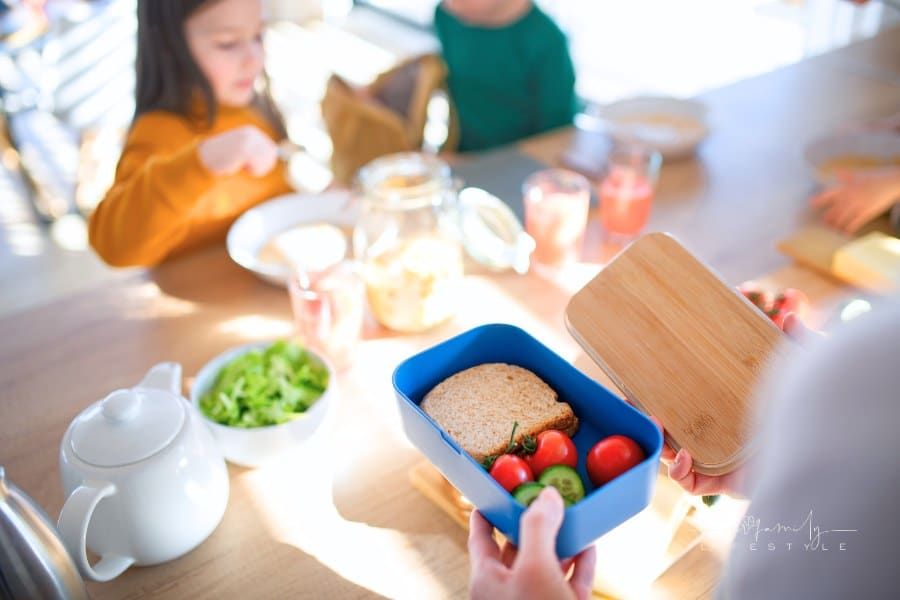 Happy Mother of Three Little Children Preparing Lunch Boxes in Kitchen at Home.
