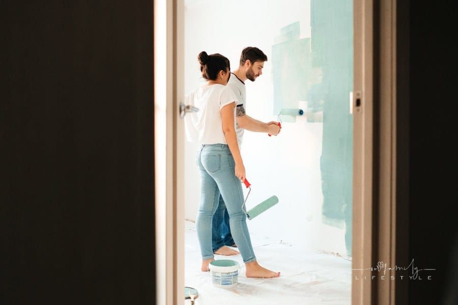 Man Painting Wall Beside a Woman holding a Paint Roller