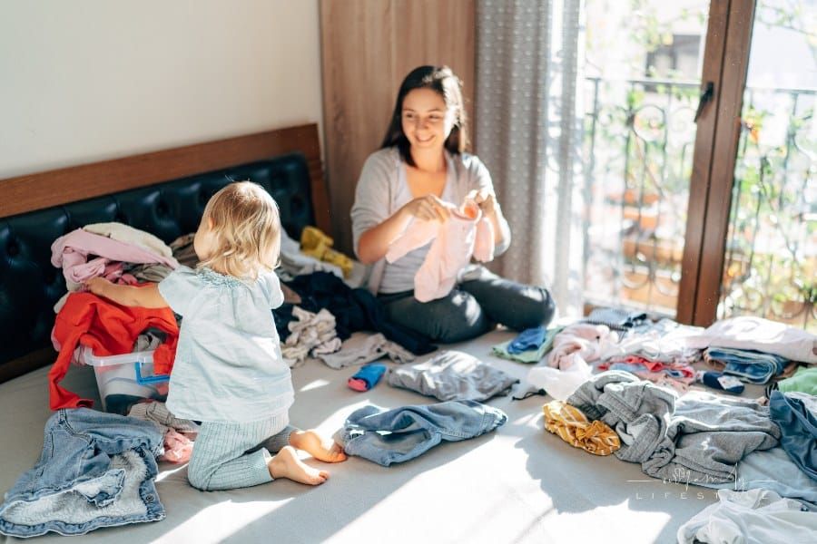 Mom and Daughter Folding Clothes on Bed