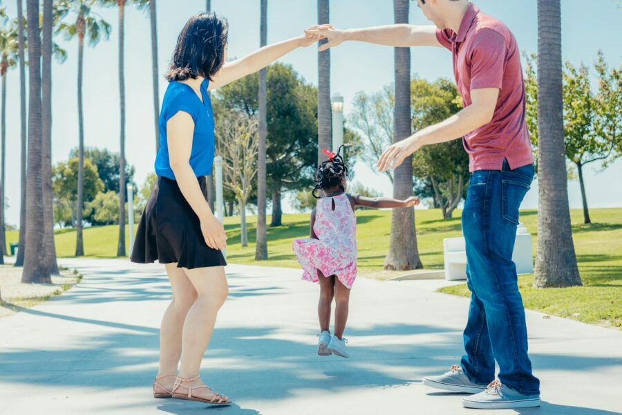Joyful family enjoying quality time together in a sunny park with palm trees.
