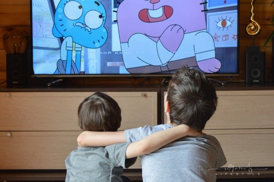 brothers with arms around each other watching cartoons