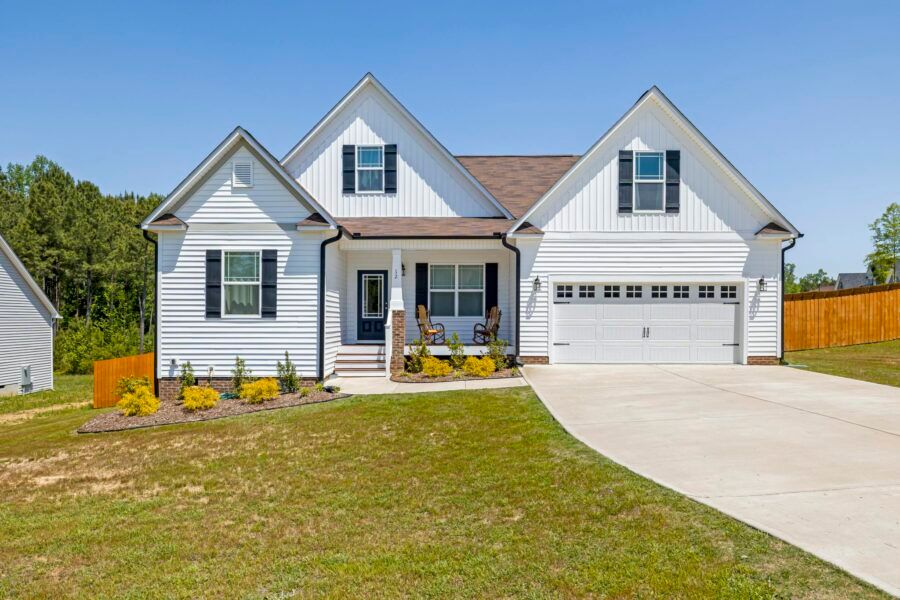 Modern white family home with garage, front yard, and blue sky background.