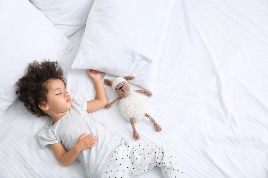 Little Girl with Stuffed Toy Sleeping in Bed