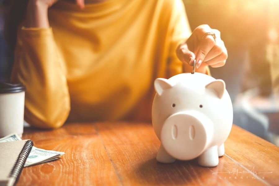 woman's hand putting change into piggy bank