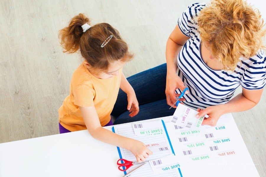 daughter helping mom cut grocery coupons