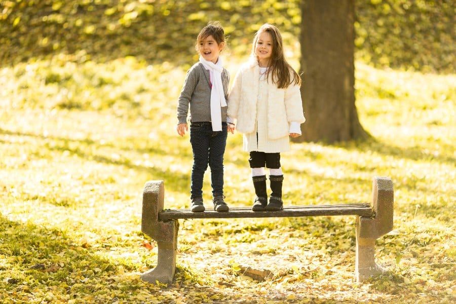 two girls on a park bench during autumn