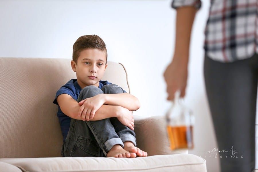Sad Little Boy and Blurred Parent with Bottle of Alcohol