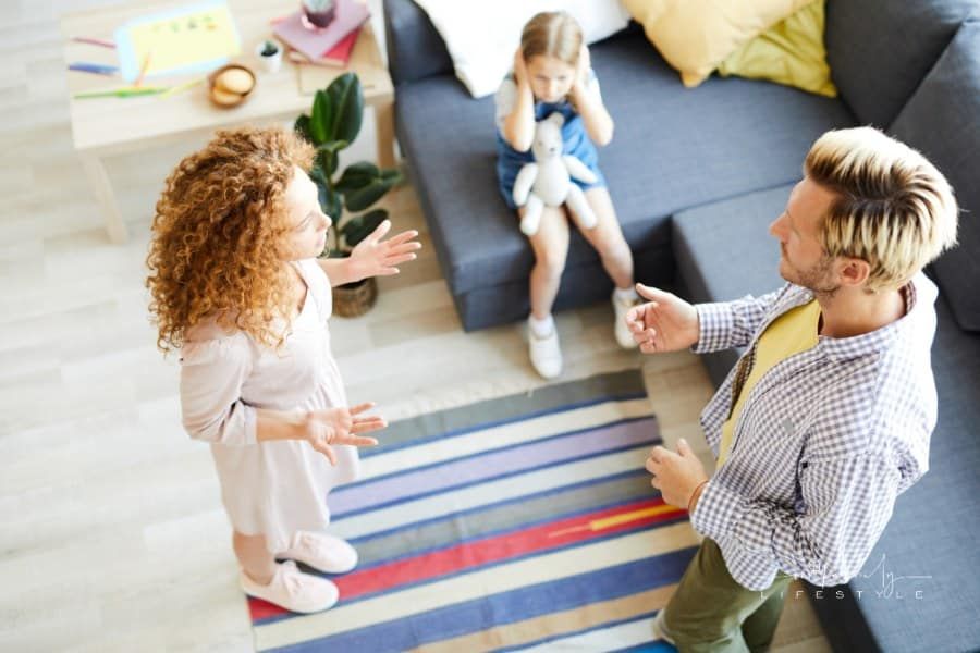 parents arguing in front of their young daughter who is covering her ears