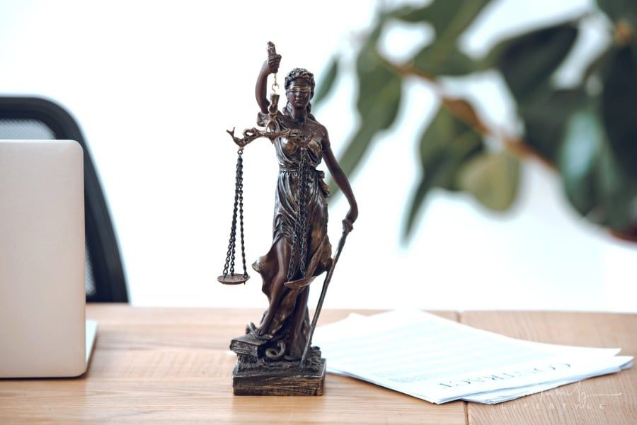close-up of Lady Justice Statue and contract on desk