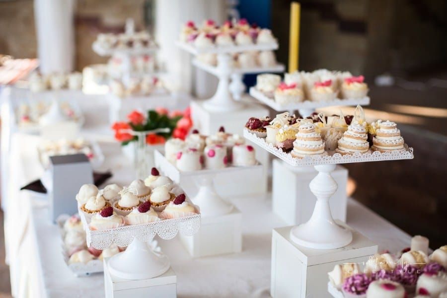 Wedding reception dessert table with delicious decorated white cupcakes with frosting closeup