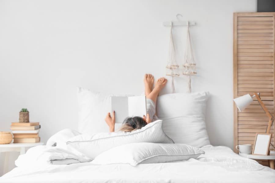 Morning of Young Woman Reading Book in Bed