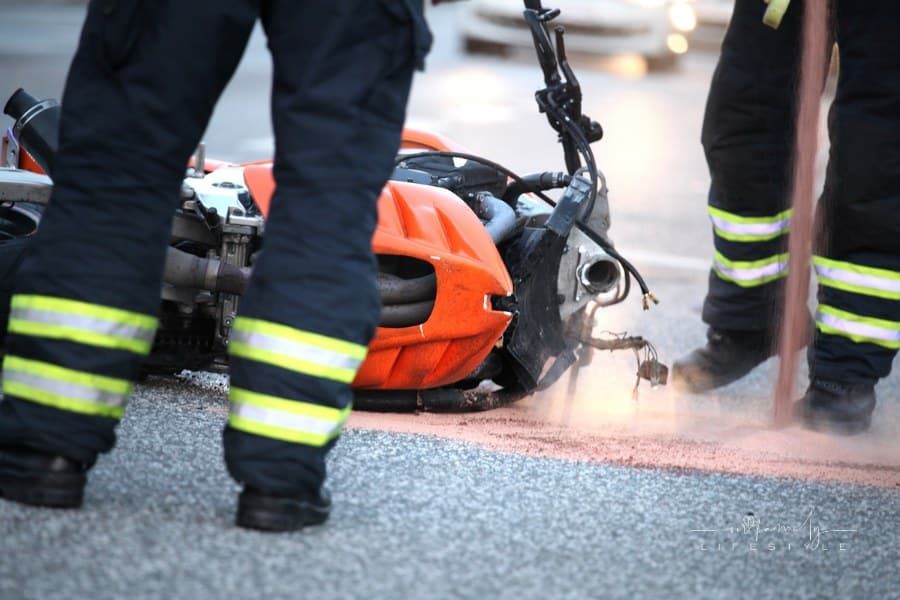 first responders standing around a motorcycle on the road after an accident