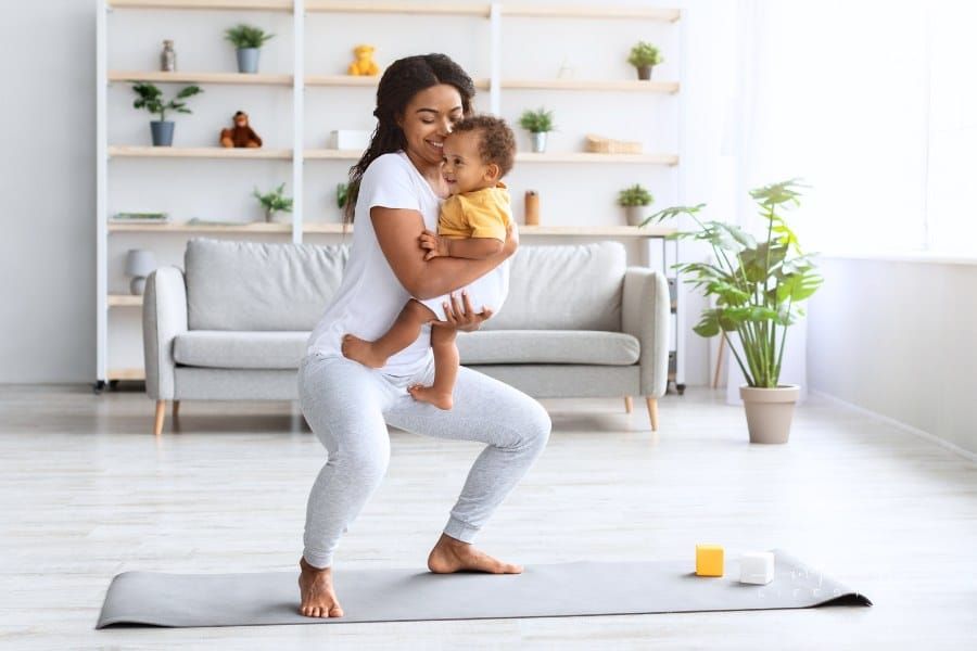 Postpartum Weight Loss. Happy Black Lady Making Squats With Baby in Hands