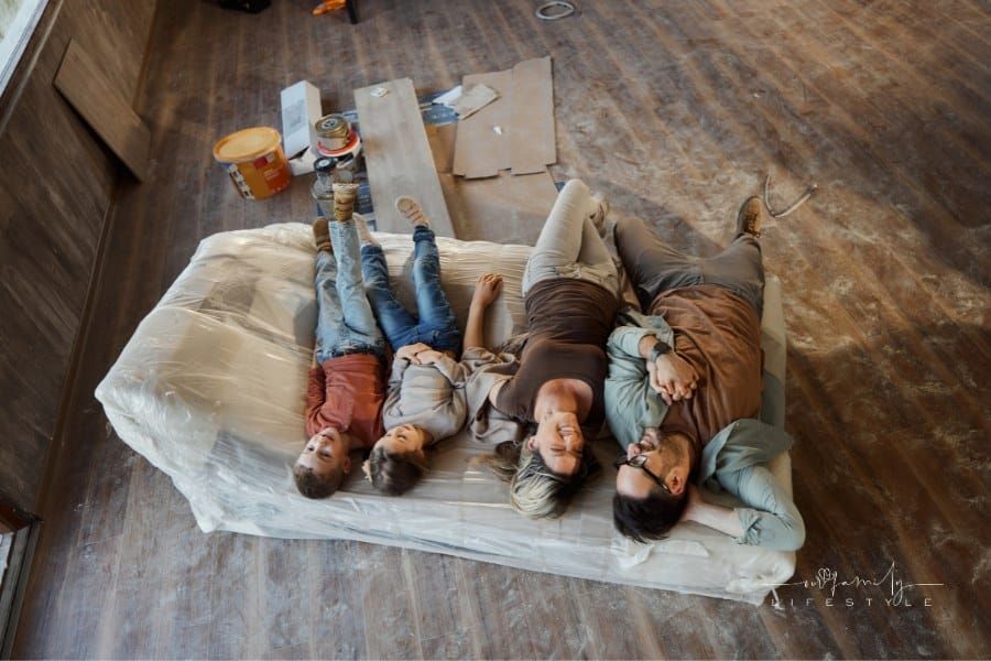 parents with small kids laying infloor with dust, paint, and tools around them during house renovation